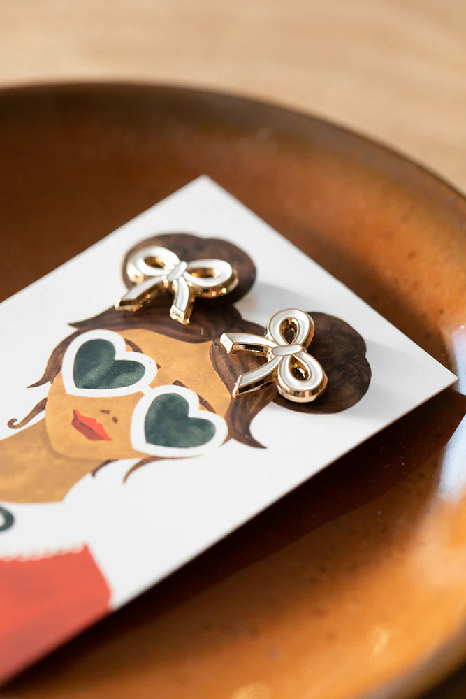 Illustration einer Person mit zwei Zöpfen, die mit weißen Schleifen verziert sind, trägt ein rotes Oberteil mit weißem Kragen und schwarzer Schleife. Darunter steht 'atws. ALL THE WAYS TO SAY'.