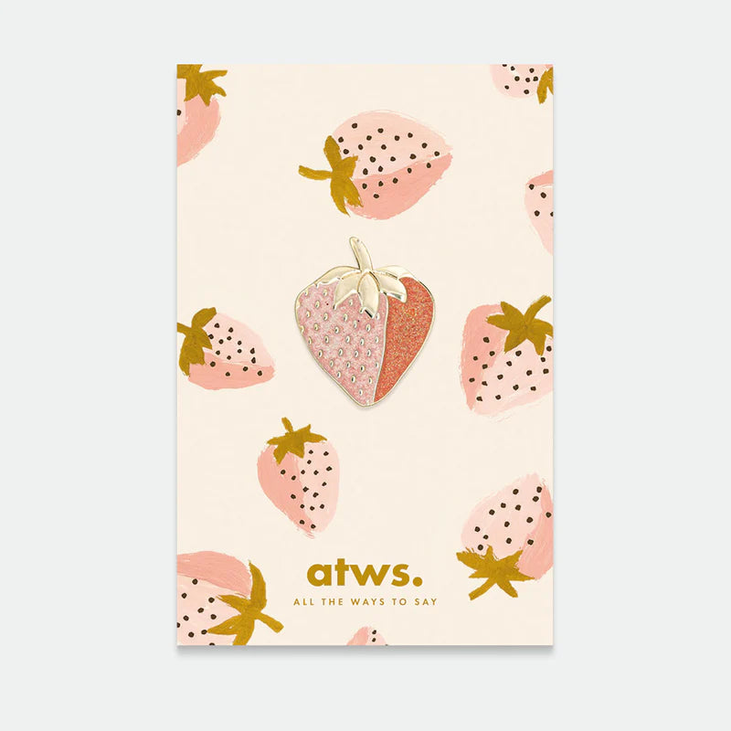 Anstecknadel in Form einer halb rosa, halb rosenroten Erdbeere mit goldfarbenem Stiel auf Karte mit rosa Erdbeermustern und Text 'atws. ALL THE WAYS TO SAY'