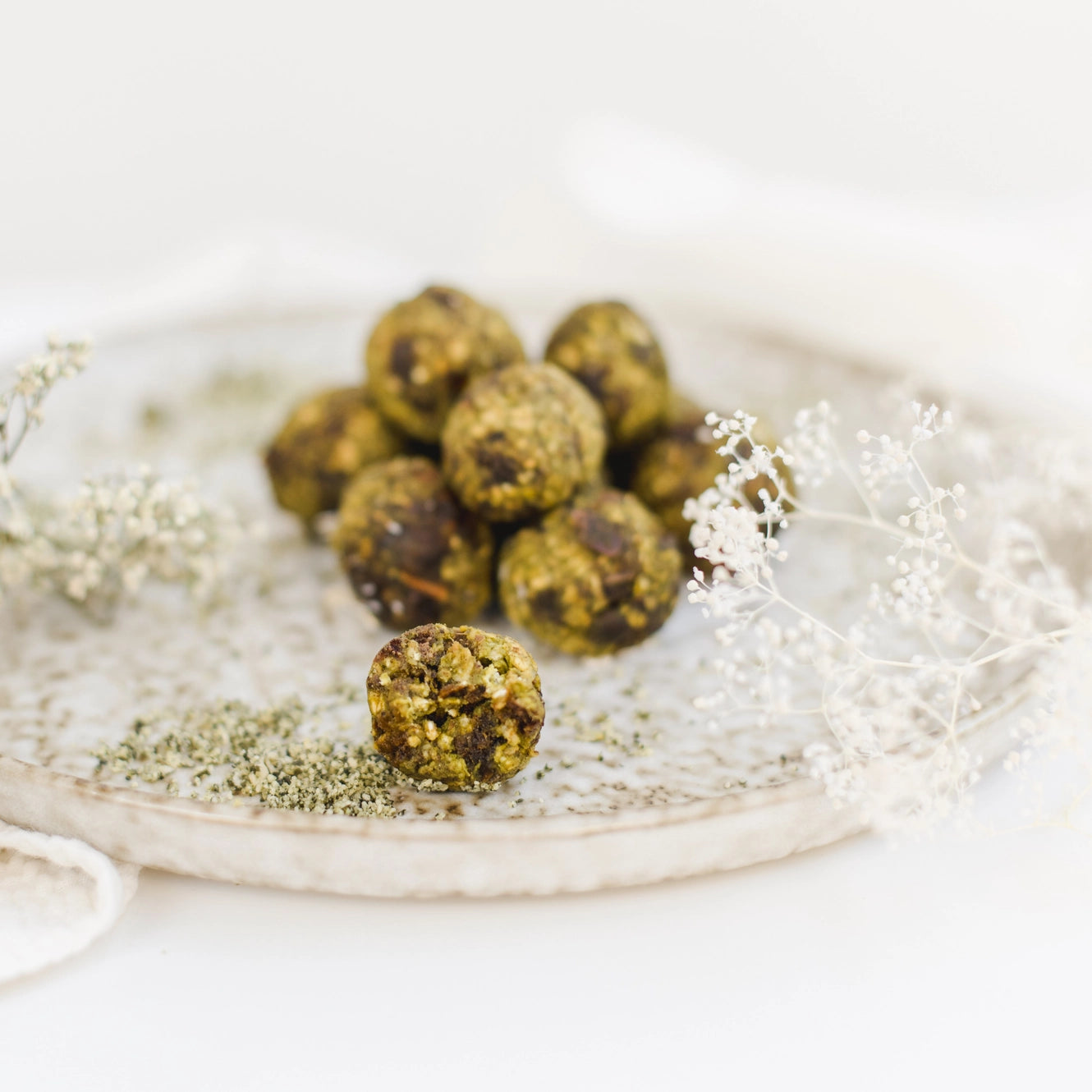 Runde grüne Power-Kugeln mit Matcha auf einem Teller.