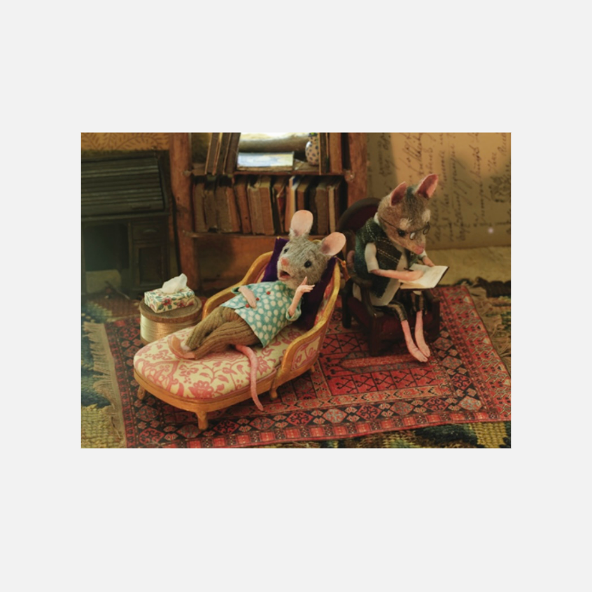 Detailansicht von zwei Mäusen in einem gemütlichen Raum, eine liest, die andere entspannt auf einer Couch.