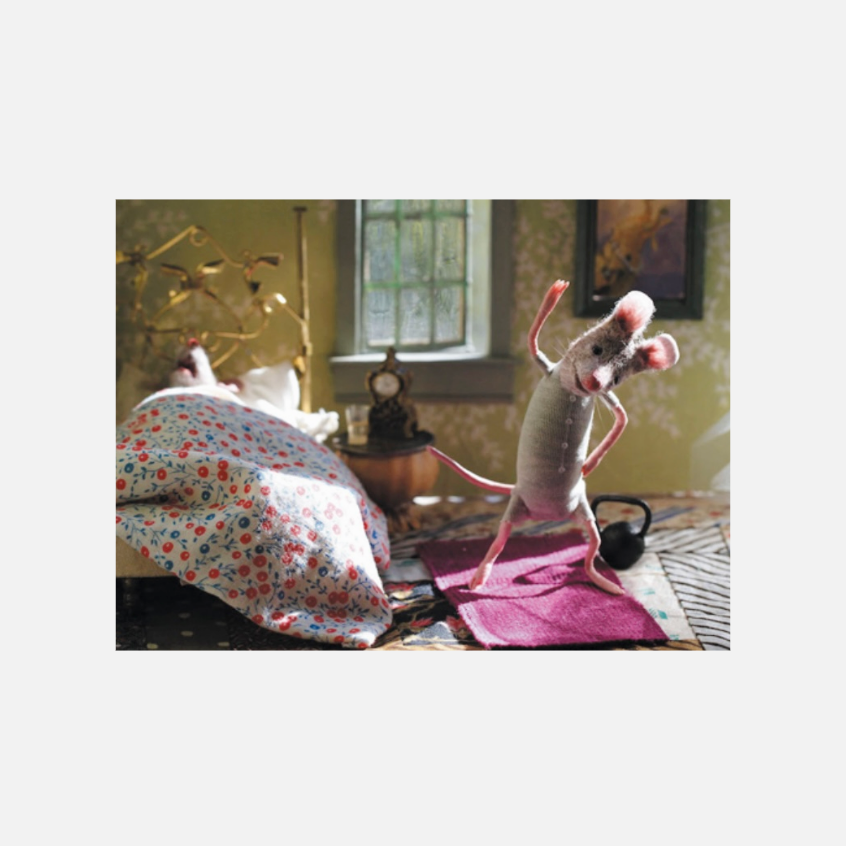 Eine anthropomorphe Maus steht auf einer Yogamatte und macht eine Dehnübung in einem gemütlichen Zimmer mit Bett und Fenster