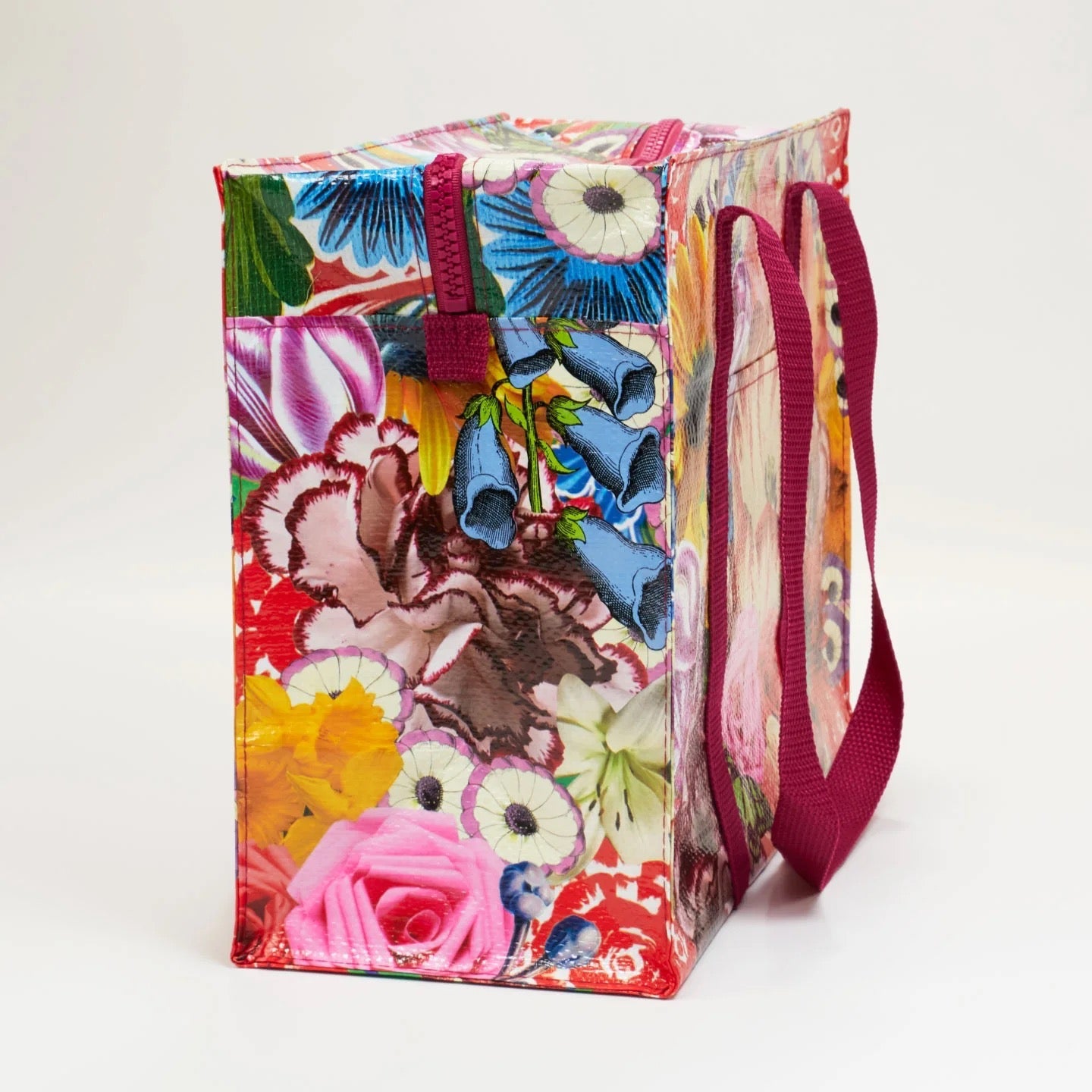 Bunte Einkaufstasche mit Blumenmuster und zwei langen, pinken Tragegriffen, seitlich