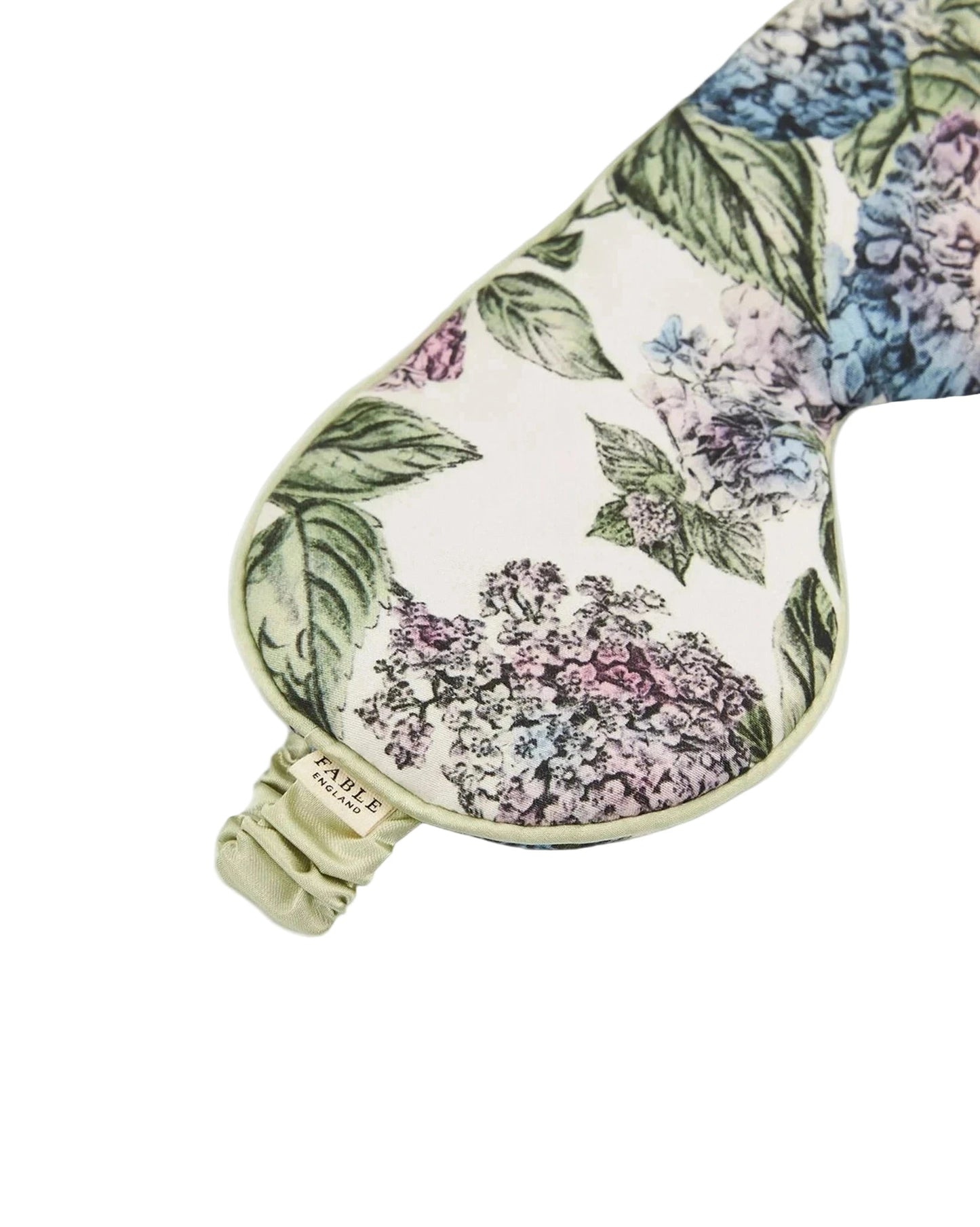 Luxuriöse Schlafmaske mit botanischem Hortensien-Design: große Blütendolden in zartem Rosa, Blau, Flieder und Grautönen mit grünen Blättern auf cremefarbenem Hintergrund, hellgrüne Satinpaspelierung und verstellbares elastisches Band in Mintgrün