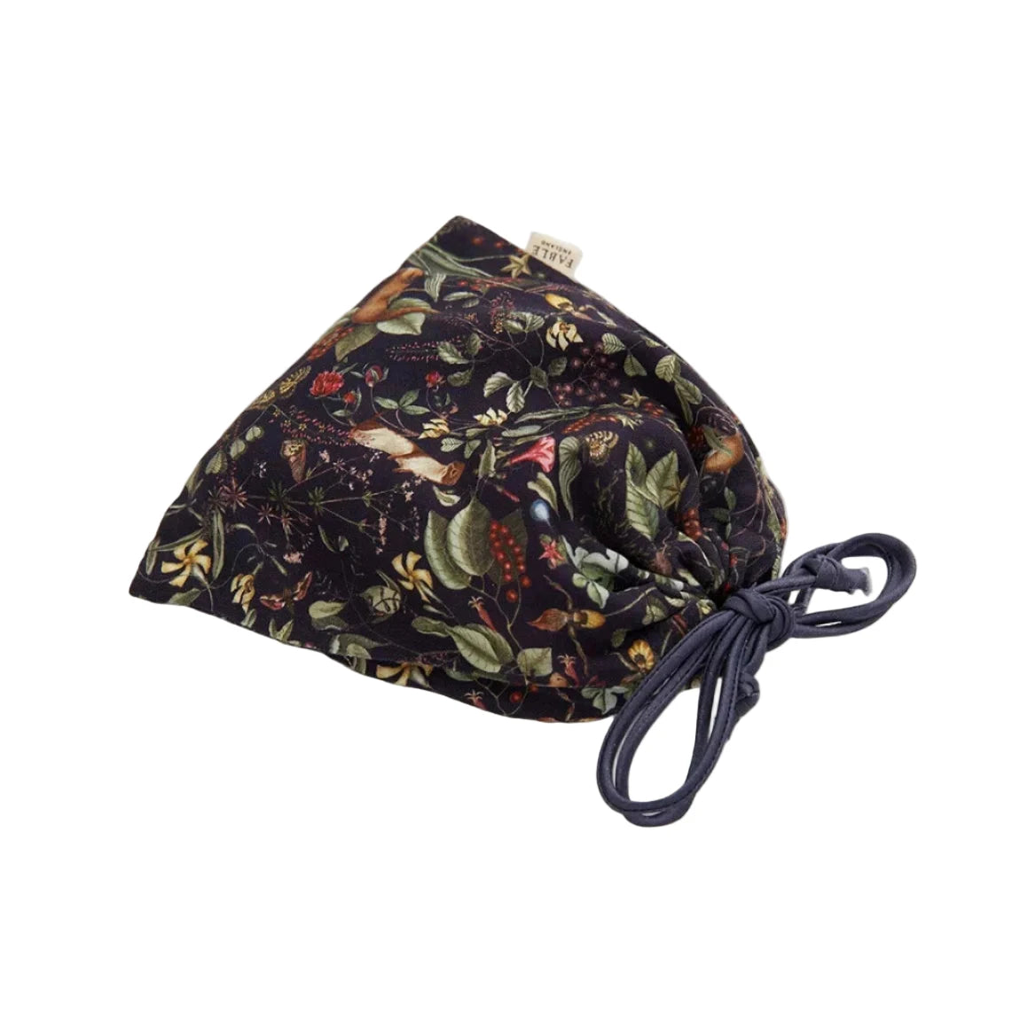 Zusammengelegte Schlafmaske mit botanischem Print in einem passenden Aufbewahrungsbeutel aus demselben Material, Beutel mit Kordelzug in Dunkelblau zum Zuziehen, Marken-Etikett sichtbar, zeigt die platzsparende Aufbewahrungslösung für unterwegs