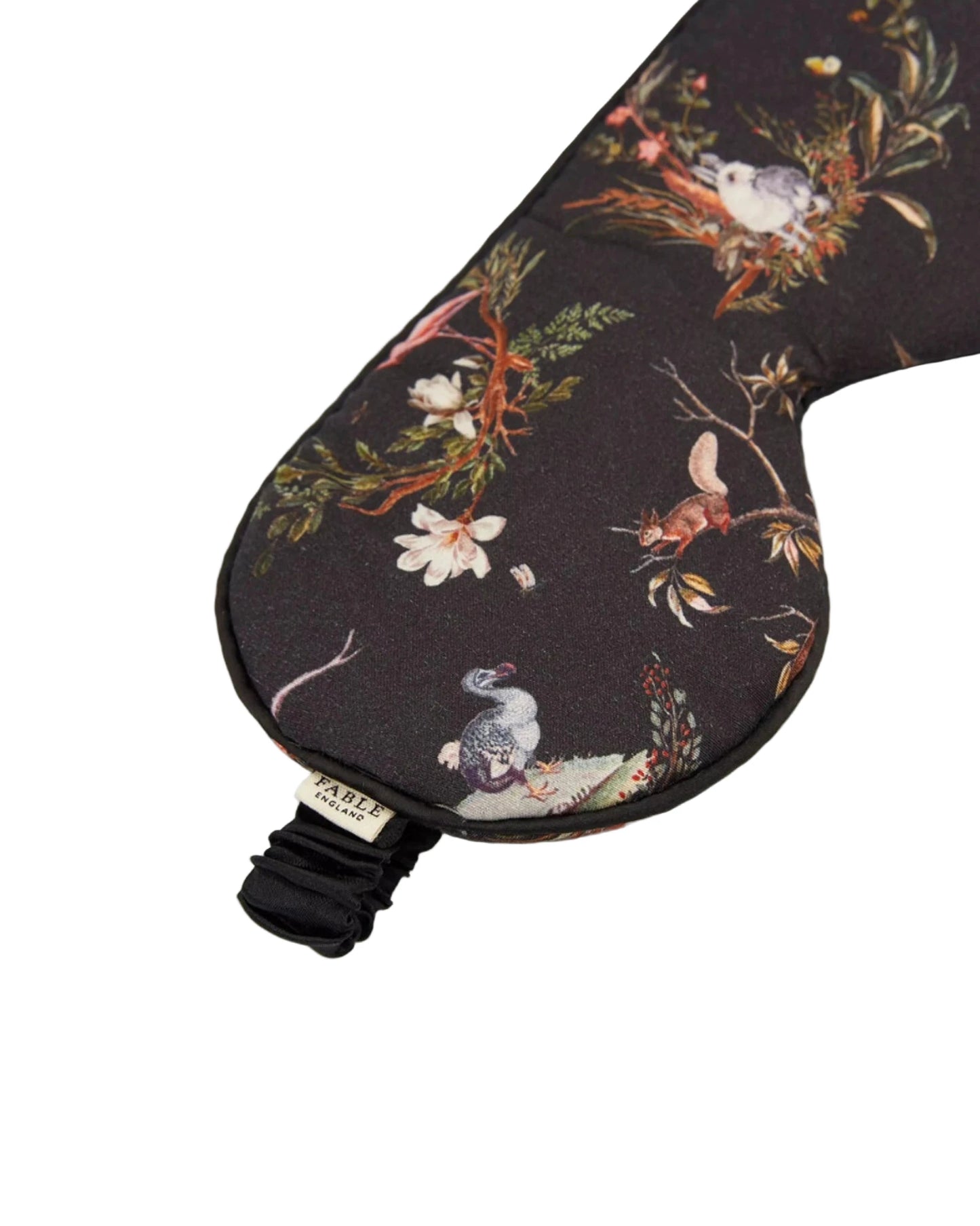 Schlafmaske mit künstlerischem Naturmotiv auf rotbraunem und schwarzem Untergrund: detaillierter Igel, Tagpfauenauge-Schmetterling, Wildblumen, Farnblätter und Beeren in warmen Herbstfarben wie Rostrot, Gelb, Grün und Orange, schwarzes Satinband mit Etikett, naturalistischer Vintage-Stil