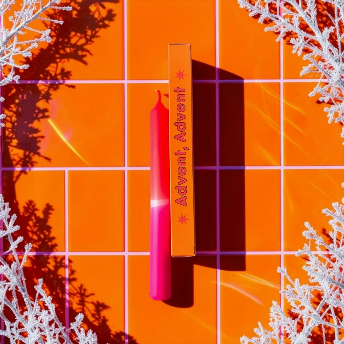 Eine kräftige Neon-Pink und Neon-Orange getauchte Stabkerze von Pink Stories im Dip-Dye-Look, mit der passenden orangen Geschenkbox und der Aufschrift „Advent, Advent