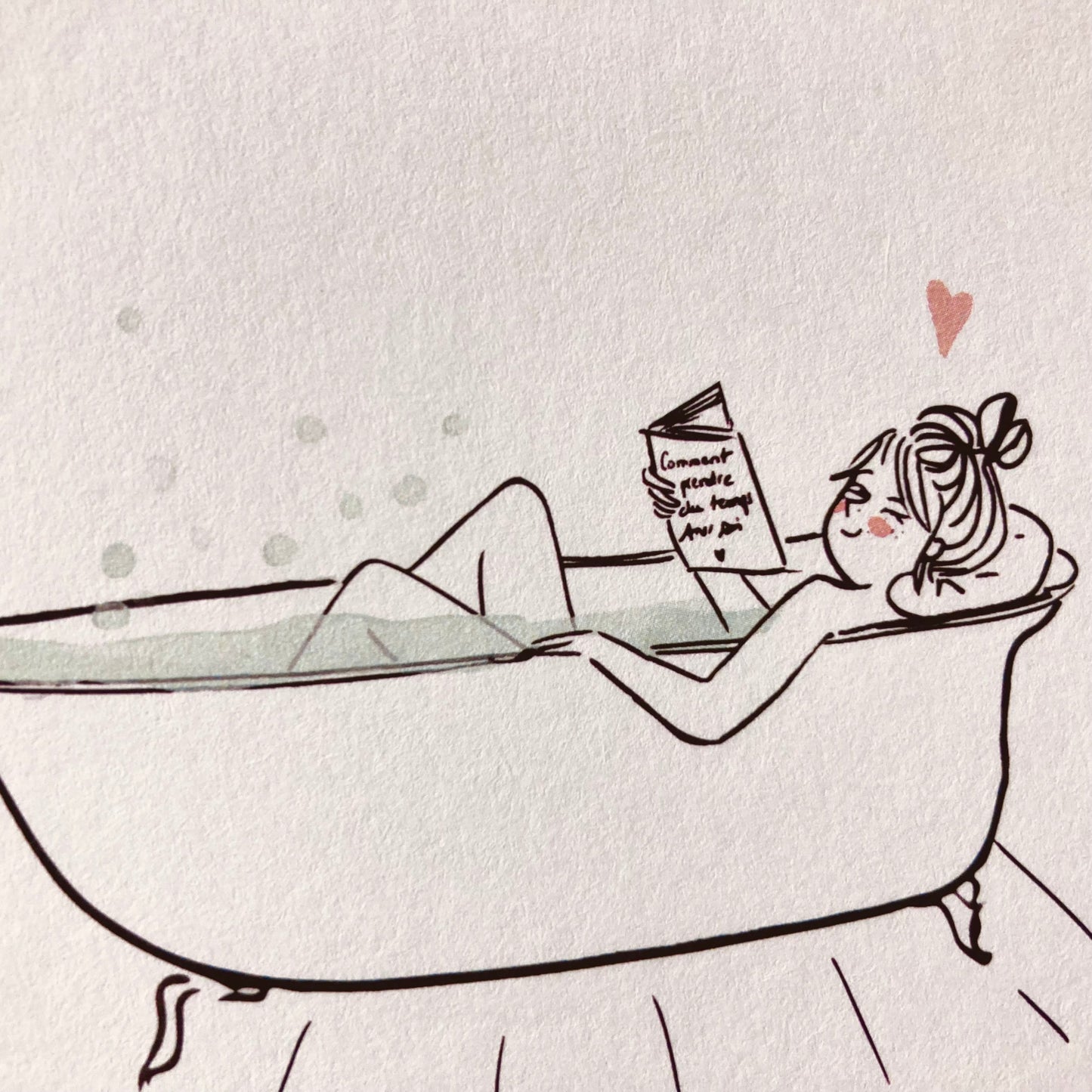 Frau entspannt in einer freistehenden Badewanne und liest ein Buch