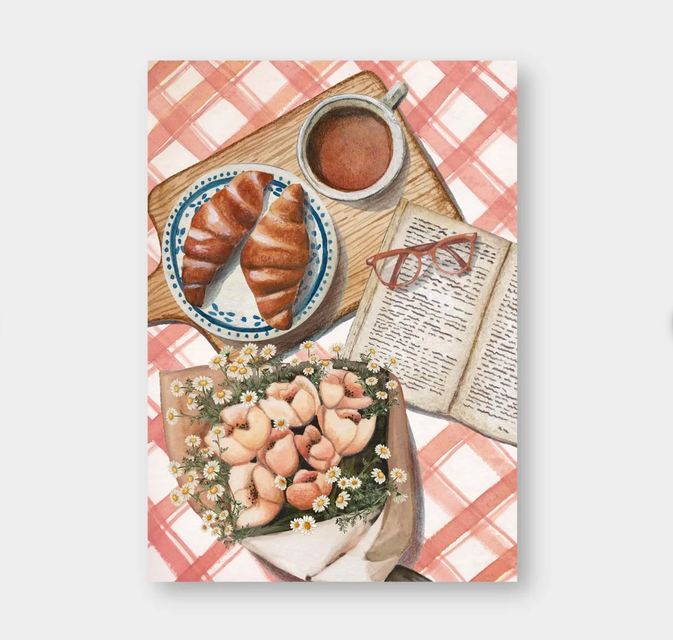 Zwei Croissants auf blau-weißem Teller, Tasse Kaffee, aufgeschlagenes Buch mit roter Brille und Blumenstrauß auf rot-weiß kariertem Tischtuch.
