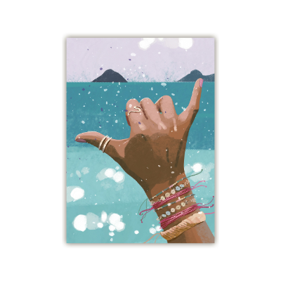 Hand mit mehreren Armbändern und Ringen zeigt Shaka-Geste vor Meer und Inseln im Hintergrund