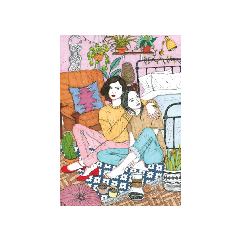 Zwei Frauen sitzen eng umarmt auf einem Teppich vor einem Bett, umgeben von Pflanzen, einem orangefarbenen Sessel und einer Stehlampe