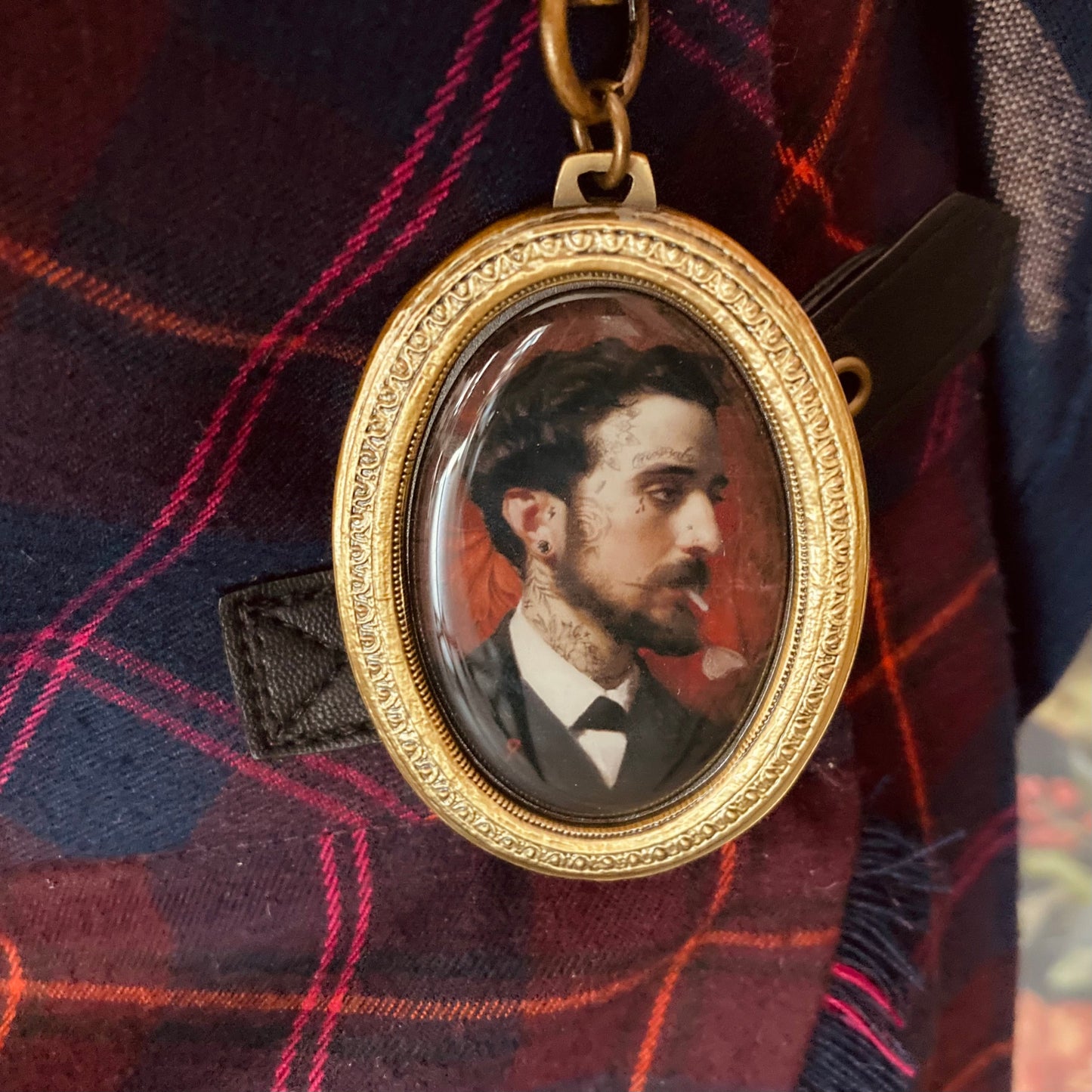 Ovaler goldener Medaillonanhänger mit einem Porträt eines Mannes in schwarzem Anzug und weißem Hemd