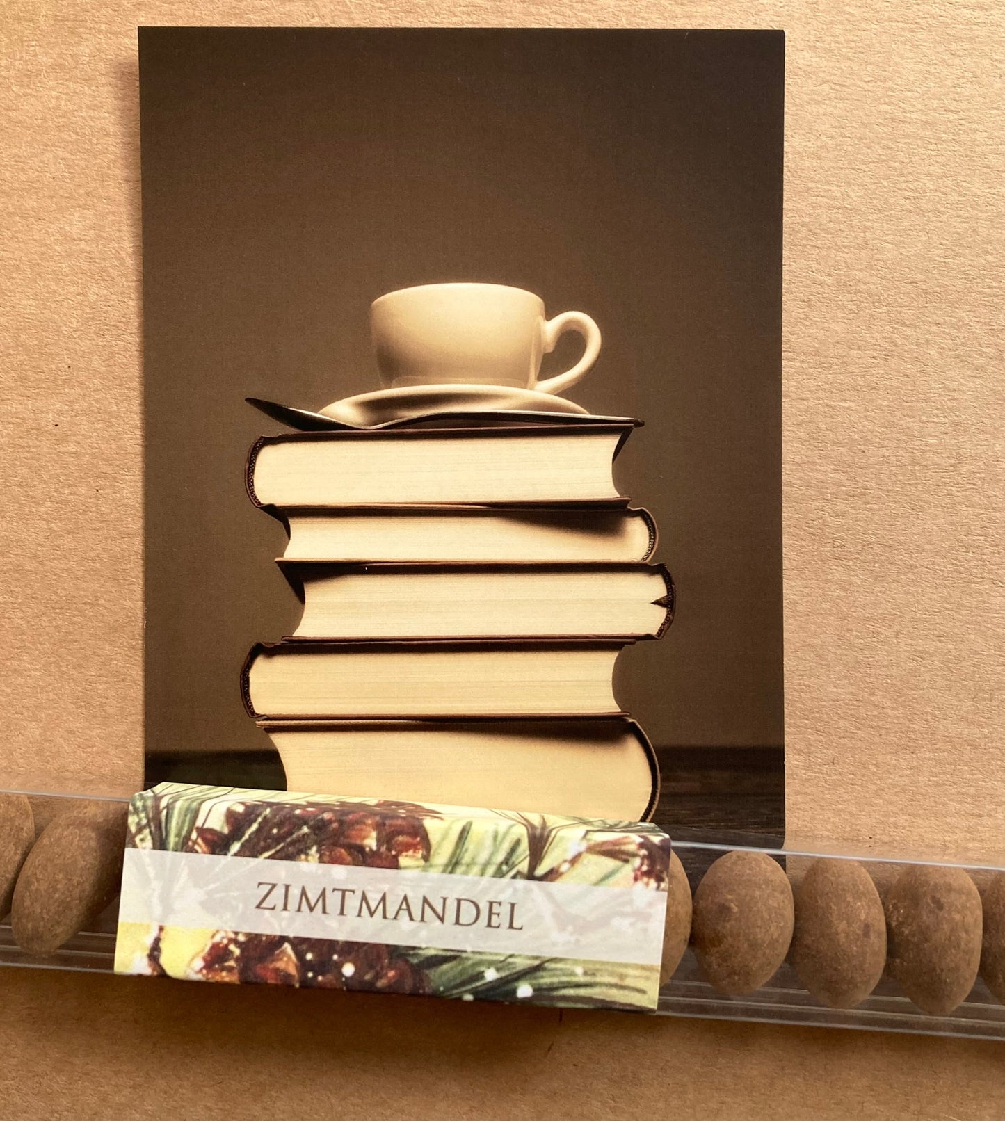 Lange, transparente Verpackung mit einer Reihe brauner Zimtmandeln und einem Etikett mit dem Schriftzug 'ZIMTMANDEL'.