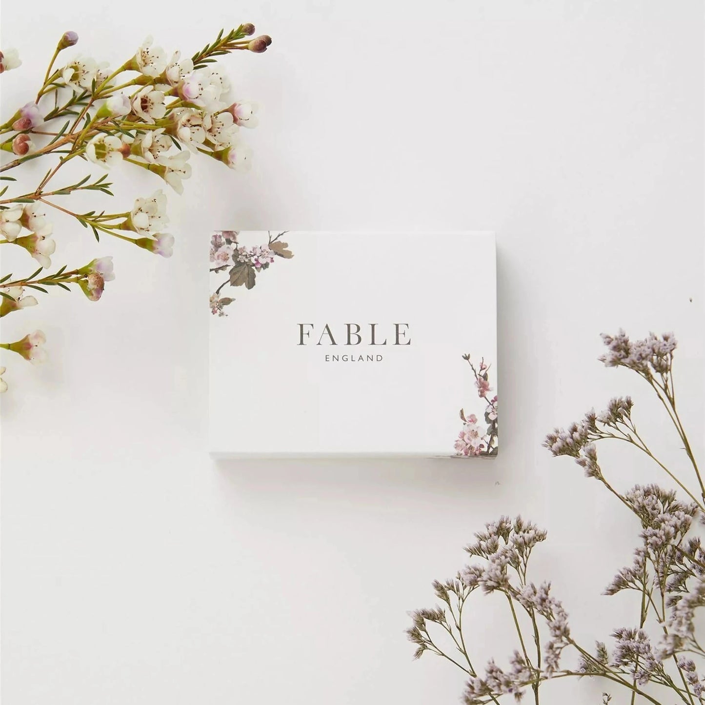 Fable England weiße Geschenkbox mit Blütenmotiv, umgeben von zarten Blumen