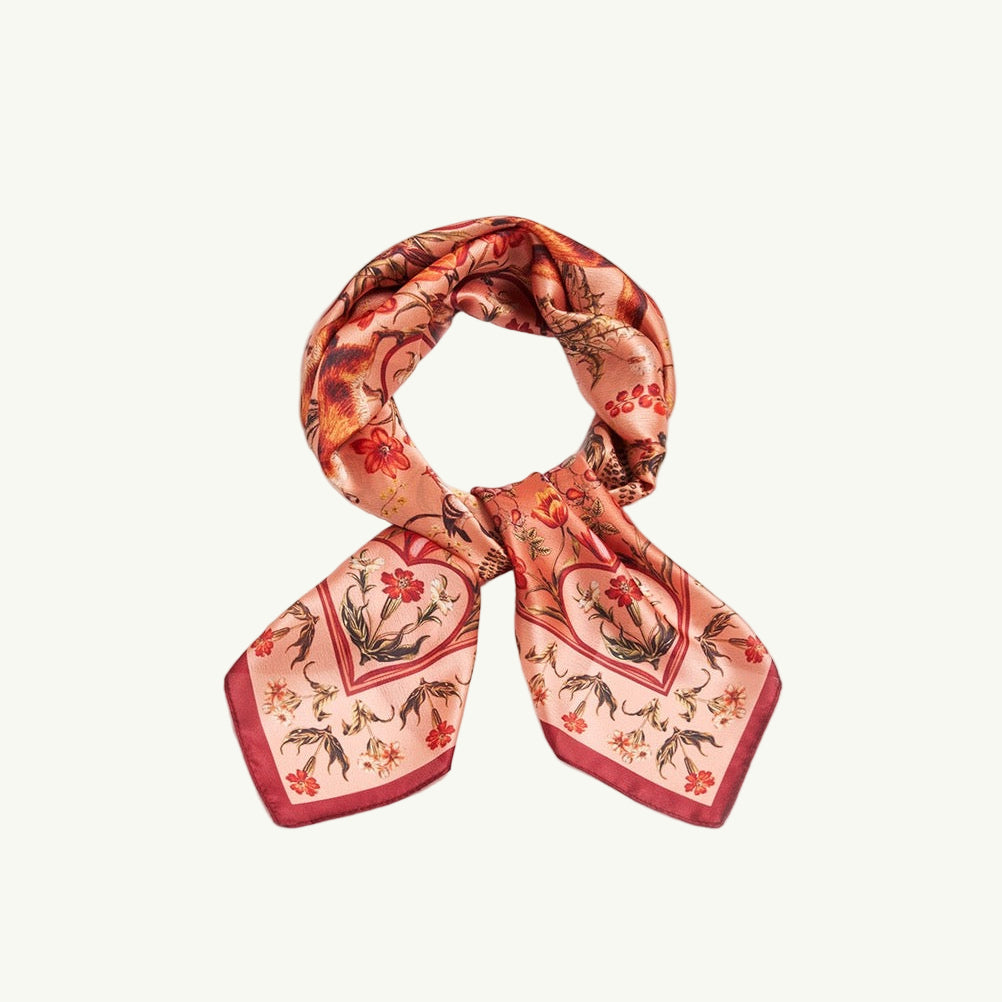 Quadratisches Tuch mit rotem Rand und floralem Muster in Rot, Blau und Beige, symmetrisch angeordnet.