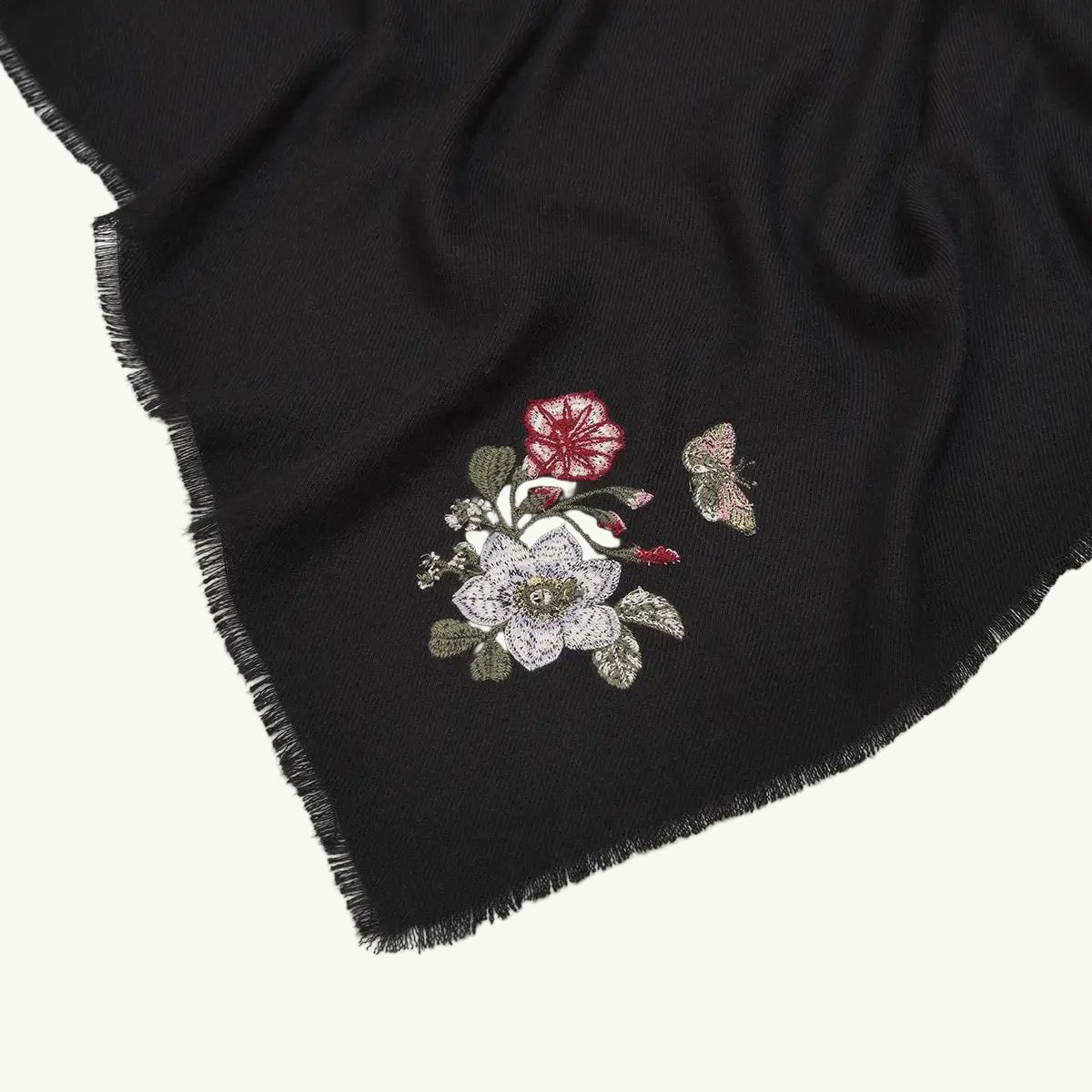Schwarzer Schal mit kurzen Fransen und besticktem Blumenmuster in Weiß, Rot und Grün.
