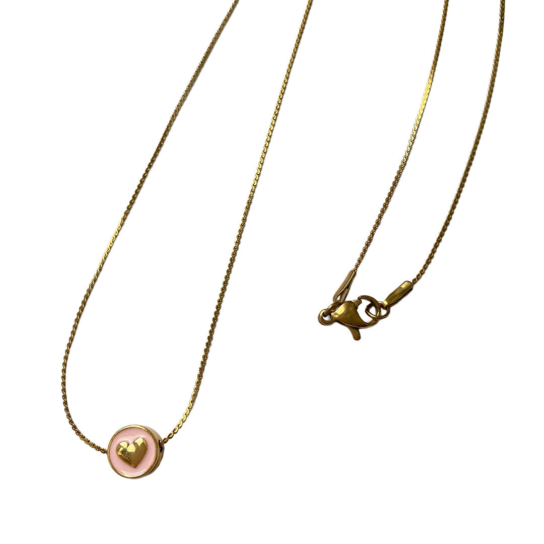 Eine sehr feine goldene Gliederkette flach liegend auf weißem Untergrund. Der runde Anhänger hat eine zartrosa Emaille-Füllung, in deren Mitte ein kleines, plastisches goldenes Herz eingearbeitet ist.
