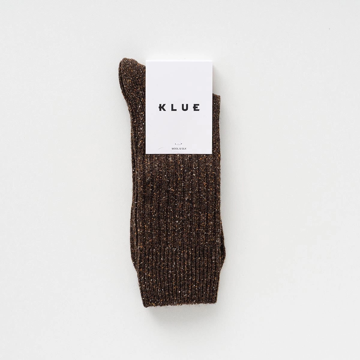Flach liegende KLUE DUST STAR Design-Socken in Braun, die die feine, hochwertige Strick-Struktur des Seiden-Woll-Gemischs zeigen.
