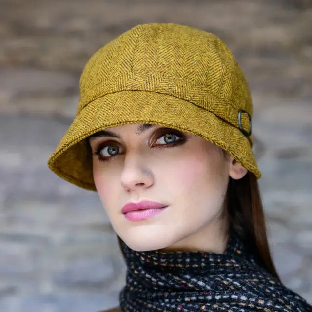 Eine Frau mit gelben Flapper Hut, grauen Schal 
vor hellem Hintergrund.