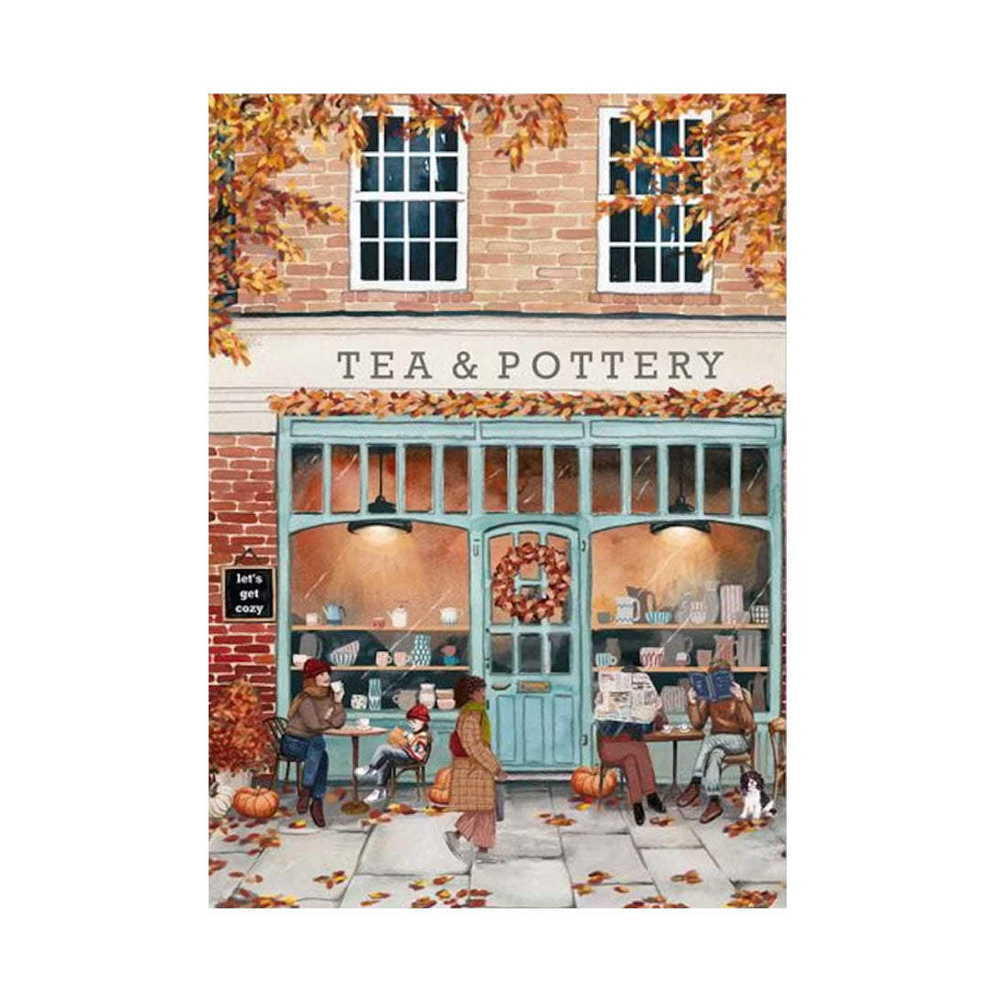 Illustration des gemütlichen Cafés „TEA & POTTERY“ im Herbst. Personen sitzen vor dem Laden an kleinen Tischen, trinken Tee und lesen Zeitung. Herbstlaub liegt auf dem Boden und Kürbisse dekorieren den Gehweg.