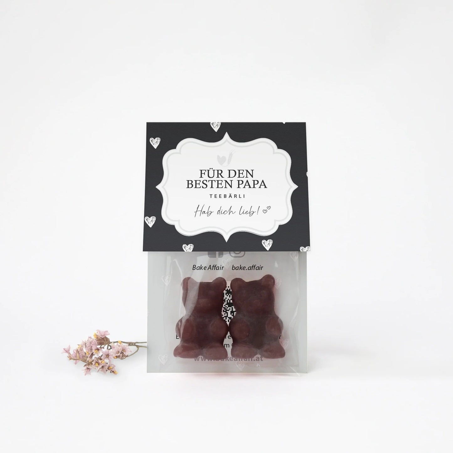 Zwei braune Bären aus Schokolade in transparenter Verpackung mit schwarzem Etikett, darauf steht 'FÜR DEN BESTEN PAPA TEEBÄRLI Hab dich lieb!'