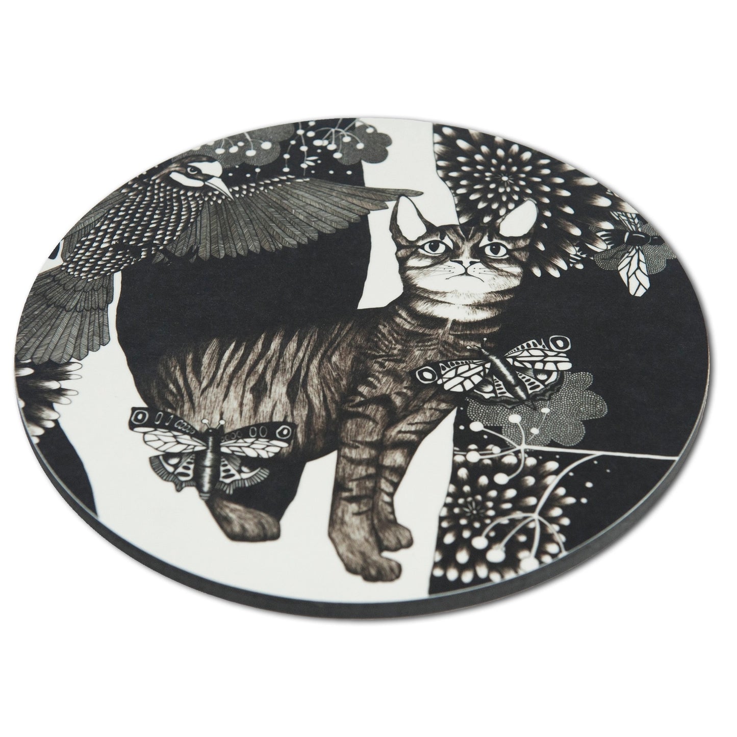Schräge Seitenansicht des runden Nadja Wedin Topfuntersetzers zeigt die flache Form und die detailreiche Grafik mit Katze, Schmetterlingen und Vogel im schwarz-weißen Design.