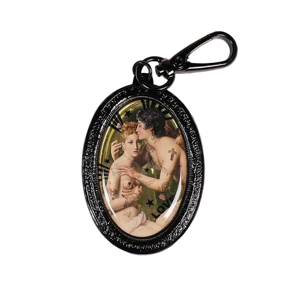 Schwarzer Schlüsselanhänger mit ovalem Rahmen, zeigt ein klassisches Gemälde zweier nackter Figuren, einer mit Kreuz-Tattoo auf dem Arm