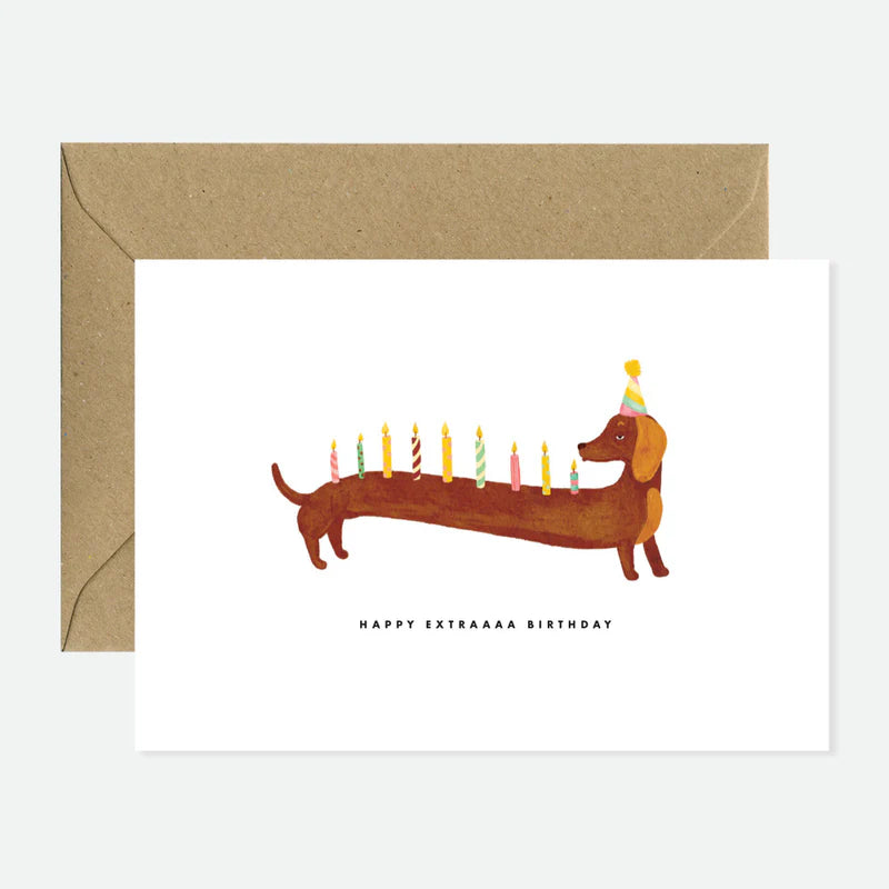 Geburtstagskarte mit langem Dackel, der Partyhut trägt und zehn bunte Kerzen auf dem Rücken hat, darunter Text 'Happy Extraaaa Birthday'