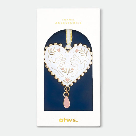 Herzförmiger Anhänger mit goldfarbenem Rand, weißem Hintergrund, zwei Tauben und floralen Mustern, rosa Tropfenanhänger, in Verpackung mit Aufschrift 'ENAMEL ACCESSORIES' und 'atws.'