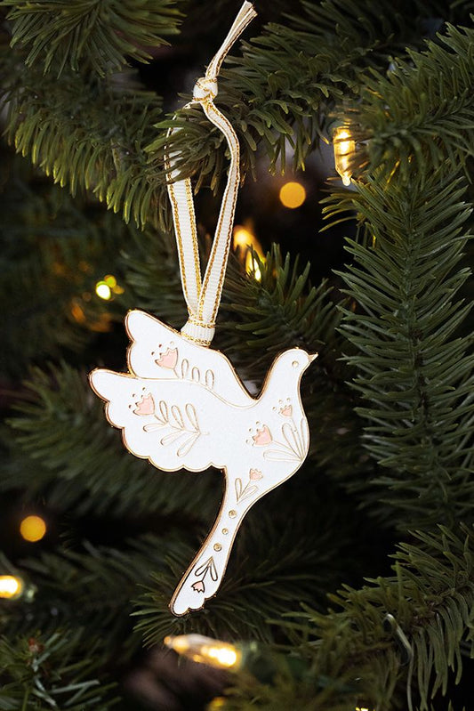 Weißer Taubenanhänger mit goldfarbenen Verzierungen hängt an einem Tannenzweig.