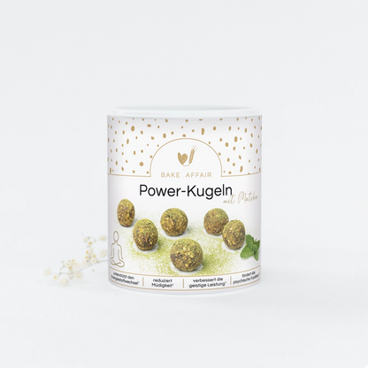 Runde grüne Power-Kugeln mit Matcha auf weißem Behälter mit goldenen Punkten und Text 'Power-Kugeln mit Matcha'.