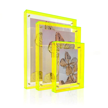 Drei transparente Acrylbilderrahmen mit neongelbem Rand, jeweils mit Einleger