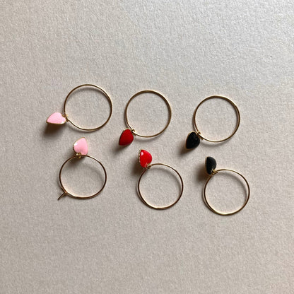 3 Paar goldfarbene Creolen mit herzförmigen Anhängern in Schwarz, Rot und Rosa, auf hellem Untergrund.