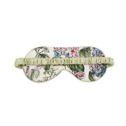 Luxuriöse Schlafmaske mit botanischem Hortensien-Design: große Blütendolden in zartem Rosa, Blau, Flieder und Grautönen mit grünen Blättern auf cremefarbenem Hintergrund, hellgrüne Satinpaspelierung und verstellbares elastisches Band in Mintgrün
