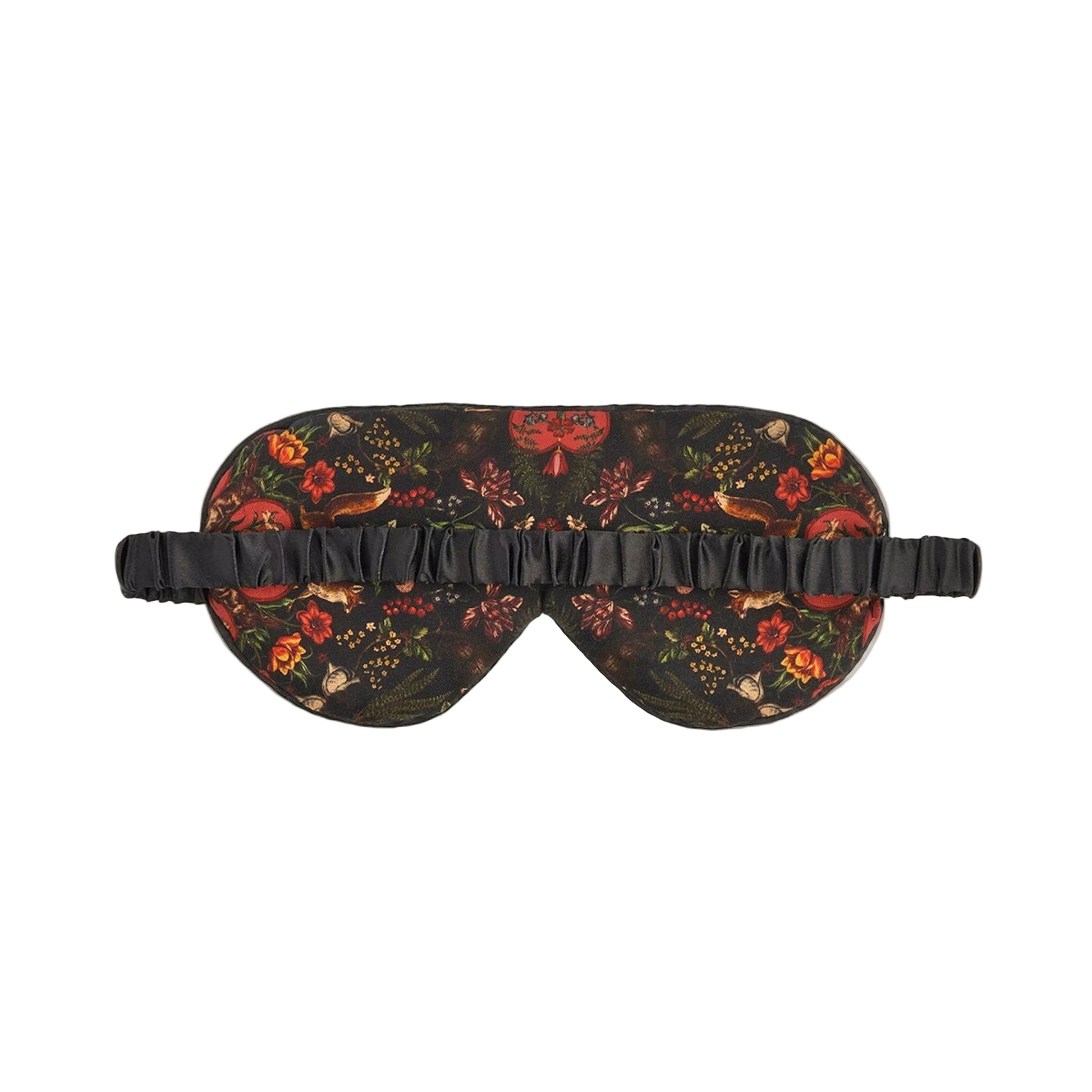 Schlafmaske mit künstlerischem Naturmotiv auf rotbraunem und schwarzem Untergrund: detaillierter Igel, Tagpfauenauge-Schmetterling, Wildblumen, Farnblätter und Beeren in warmen Herbstfarben wie Rostrot, Gelb, Grün und Orange, schwarzes Satinband mit Etikett, naturalistischer Vintage-Stil
