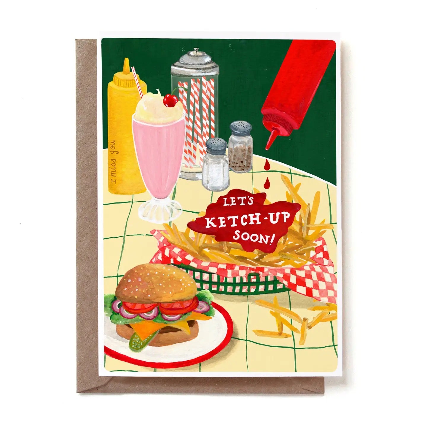Eine illustrierte Grußkarte im Diner-Stil mit dem humorvollen Text „LET'S KETCH-UP SOON!“, der in einen großen roten Ketchup-Fleck geschrieben ist. Aus einer schwebenden roten Flasche tropft Ketchup auf den Fleck. Auf dem gelb-grün karierten Tisch stehen ein saftiger Cheeseburger, eine Korb-Schale mit Pommes frites, ein rosa Milchshake mit einer Kirsche sowie Salz- und Pfefferstreuer. Auf der gelben Senfflasche im Hintergrund steht dezent „I miss you“. Die Karte steckt in einem braunen Kraftpapier-Umschlag.