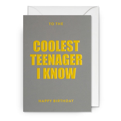Graue Geburtstagskarte mit gelbem Text 'TO THE COOLEST TEENAGER I KNOW' und 'HAPPY BIRTHDAY', dazu ein weißer Umschlag.