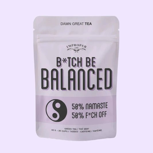Teebeutelverpackung mit der Aufschrift 'B*TCH BE BALANCED', darunter ein Yin-Yang-Symbol und der Text '50% NAMASTE 50% F*CK OFF', oben 'DAMN GREAT TEA'.