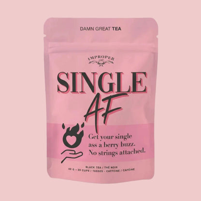 Rosa Verpackung mit schwarzem Text 'SINGLE AF', 'DAMN GREAT TEA', 'Get your single ass a berry buzz. No strings attached.', schwarzes Symbol einer Hand mit Herzflamme, Produktbeschreibung schwarzer Tee