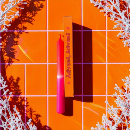 Eine kräftige Neon-Pink und Neon-Orange getauchte Stabkerze von Pink Stories im Dip-Dye-Look, mit der passenden orangen Geschenkbox und der Aufschrift „Advent, Advent