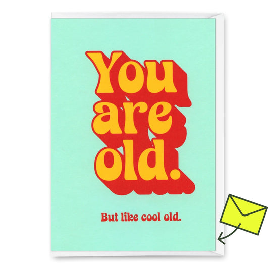 Eine humorvolle Geburtstagskarte mit einem mintgrünen Hintergrund und großem, orange-rotem Retro-Text: „You are old.“ Darunter steht in kleinerem roten Text: „But like cool old.“ In der oberen rechten Ecke befindet sich ein gelber „Deli Cards“-Aufkleber. 