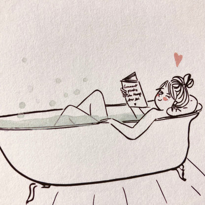 Frau entspannt in einer freistehenden Badewanne und liest ein Buch