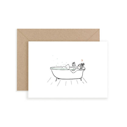 Frau entspannt in einer freistehenden Badewanne und liest ein Buch