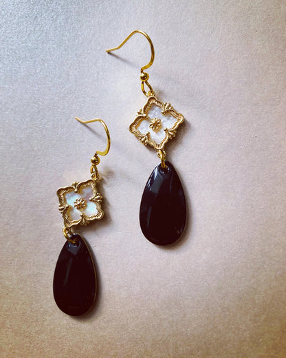 Ohrringe mit goldfarbenen Haken, goldfarbenen Perlmutt-Verbinder und schwarzen, tropfenförmigen Anhängern.