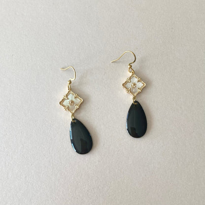 Ohrringe mit goldfarbenen Haken, goldfarbenen Perlmutt-Verbinder und schwarzen, tropfenförmigen Anhängern.