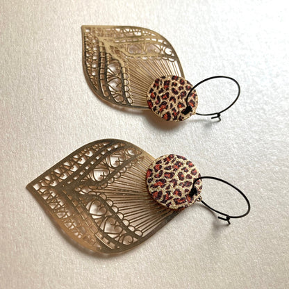 Ohrringe mit kleinen,runden,Leopard Muster Aufhängern und goldfarbenen, filigran geschnittenen Blattformen.