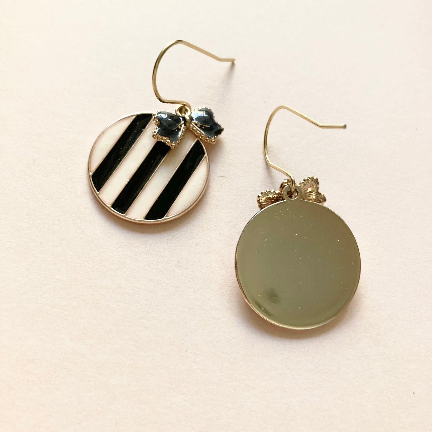 Runde Ohrringe mit schwarz-weißen diagonalen Streifen und kleinen schwarzen Schleifenverzierungen am oberen Rand.