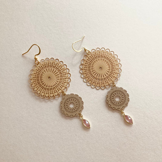 Goldfarbene Ohrringe mit filigranen, runden Mandala-Vebindern und tropfenförmigen, rosafarbenen Anhängern.