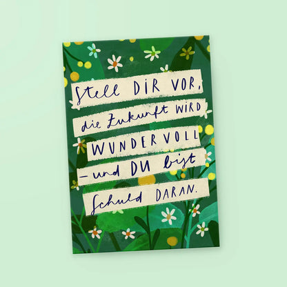 Grüne Karte mit weißen Blumen und dem Text 'Stell dir vor, die Zukunft wird wundervoll – und du bist schuld daran.'