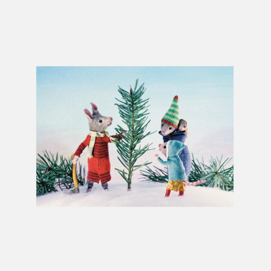 Drei kleine Mäuse aus Filz, eine in rotem Pullover und eine mit grün-weiß gestreiftem Mütze, stehen im Schnee neben einem kleinen Tannenbaum