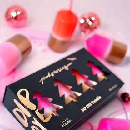 Schwarze Verpackung mit goldener Schrift und Aussparungen in Form von Tannenbäumen, darin vier bunte Kerzen, umgeben von rosa und roten Weihnachtskugeln und Kerzen.